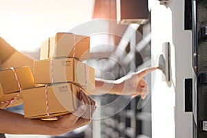 Delivery man holding parcel boxes and ring the doorbell on the client`s door in the morning background