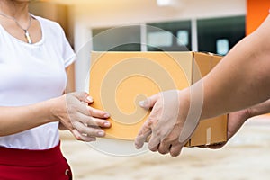 Delivery man holding pile of cardboard boxes in front delivering package to customer, close up at hand and box