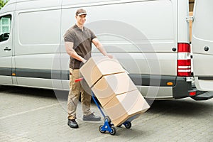 Delivery Man Holding Trolley With Cardboard Boxes