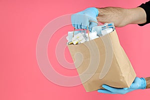 Delivery man holds bag with medicines on pink background