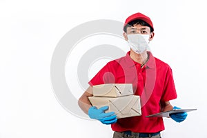 Delivery man in medical safety mask holding and carrying delivery boxes and tablet