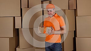 Delivery man in orange uniform delivering damaged parcel to customer. Brown cartons background. Flaw and unprofessional