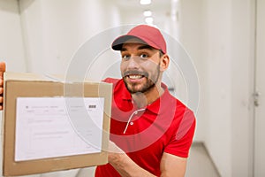 Delivery man with parcel box in corridor