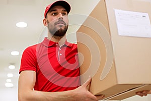 Delivery man with parcel box in corridor