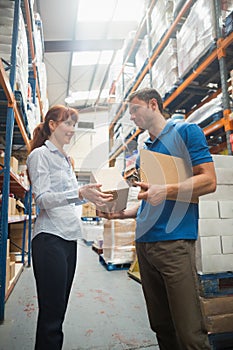Delivery man passing parcel to warehouse manager