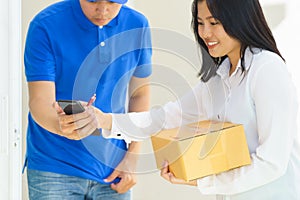 Delivery man pointing on smartphone and woman receiving package