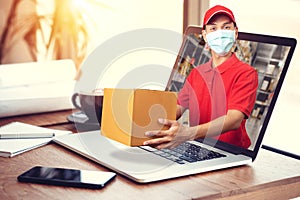 Delivery man in red shirt with hygienic mask, holding goods order in package parcel out from laptop computer with warehouse