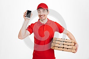 Delivery man in red t-shirt and cap holding stack of pizza boxes