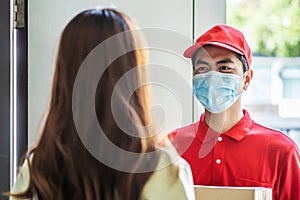 Delivery man in red uniform holding parcel boxes to a woman customer - courier service concept