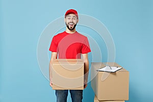 Delivery man in red uniform isolated on blue background, studio portrait. Male employee in cap t-shirt print working as