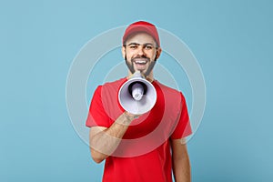 Delivery man in red workwear scream in megaphone isolated on blue background studio portrait. Professional male employee