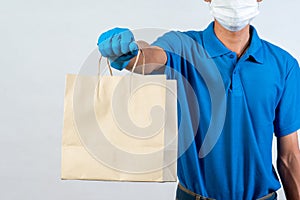 Delivery man with rubber gloves holding paper bag