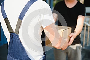 Delivery man service with boxes in hands standing in front of Customer`s house doors