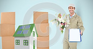 Delivery man showing clipboard while holding flowers by parcels and 3d house