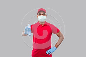 Delivery Man Showing Hands Sanitizer Wearing Medical Mask and Gloves Isolated. Indian Delivery Boy Holding Hand Antiseptic