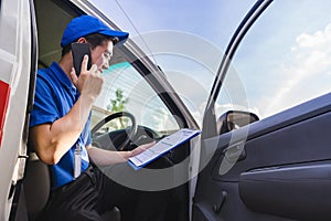 Delivery man sitting on van seat and calling to customer.