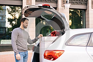 Delivery man standing near car, large festive white box with beautiful red bow at truck.