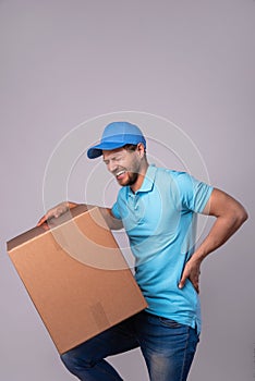 Delivery man suffering from a back pain while carrying heavy box