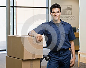 Delivery man in uniform posing with stack of boxes