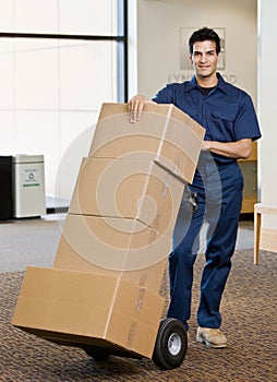 Delivery man in uniform pushing stack of boxes