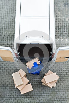 Delivery Man Unloading Cardboard Boxes From Van On Street