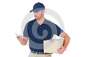 Delivery man using mobile phone while holding package