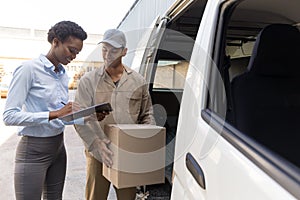 Delivery man and warehouse manager discussing over clipboard outside the warehouse