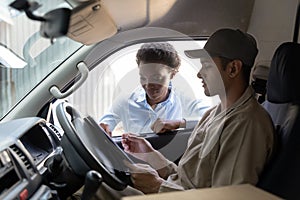 Delivery man and warehouse manager discussing over clipboard outside the warehouse