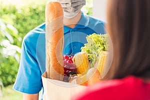 Delivery man wear protective face mask making grocery giving fresh food to woman customer