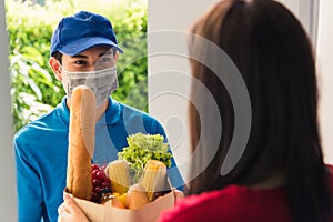 Delivery man wear protective face mask making grocery giving fresh food to woman customer