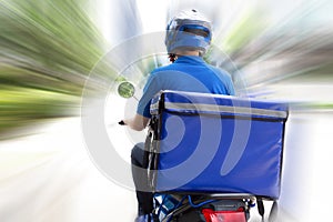 Delivery man wearing blue uniform riding motorcycle and delivery box. Motorbike delivering food.