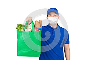 Delivery man wearing medical mask holding grocery shopping bag in supermarket