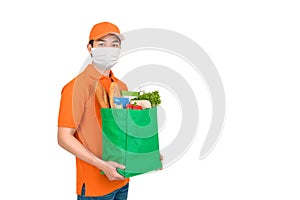 Delivery man wearing medical mask holding grocery shopping bag in supermarket