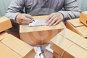 Delivery man writing on cardboard box for delivery