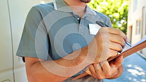 Delivery man writing on clipboard