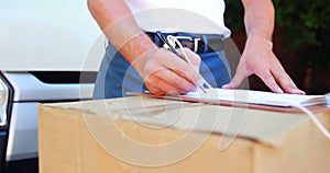 Delivery man writing on clipboard