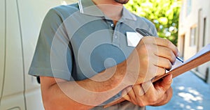 Delivery man writing on clipboard