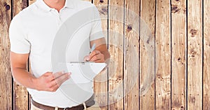 Delivery man writing on clipboard against wooden background