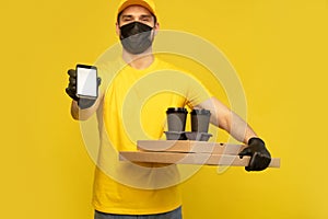 Delivery man in yellow t-shirt, mask, gloves isolated. Guy hold takeaway cup of coffee. Coronavirus 2019-ncov concept