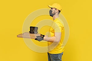 Delivery man in yellow t-shirt, mask, gloves isolated. Guy hold takeaway cup of coffee. Coronavirus 2019-ncov concept