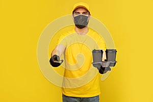 Delivery man in yellow t-shirt, mask, gloves isolated. Guy hold takeaway cup of coffee. Coronavirus 2019-ncov concept