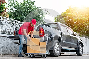 Delivery men in red uniform unloading cardboard boxes from pickup truck