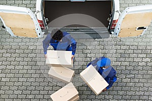 Delivery Men Unloading The Cardboard Boxes