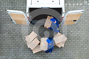 Delivery Men Unloading Cardboard Boxes From Truck On Street