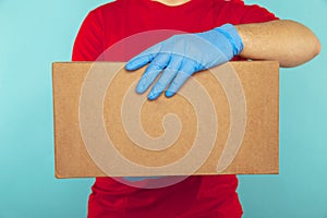 Delivery package concept. Courier in red T-shurt holding box isolated over the blue background.