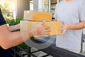 Delivery service concept, customer hand receiving a cardboard boxes parcel from delivery man at home