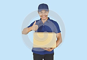 Delivery service concept.  Delivery man holding box and showing like on blue background