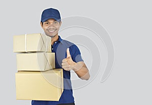 Delivery service concept.  Delivery man holding box and showing like on blue background