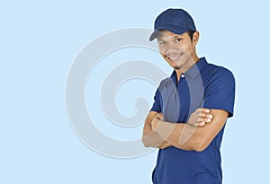 Delivery service concept. Portrait delivery man standing with arms crossed on blue background. looking at camera