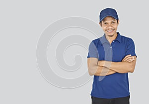 Delivery service concept. Portrait delivery man standing with arms crossed on grey background. looking at camera